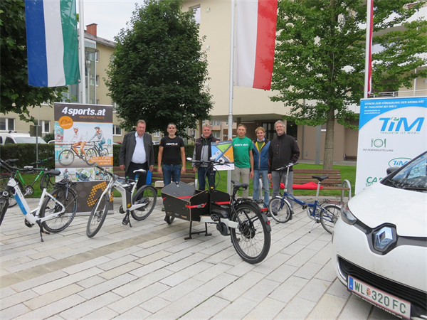 Bürgermeister, Amtsleiter und einige Veranstalter stehen am Marktplatz mit Fahrrädern und dem Renault ZOE.
